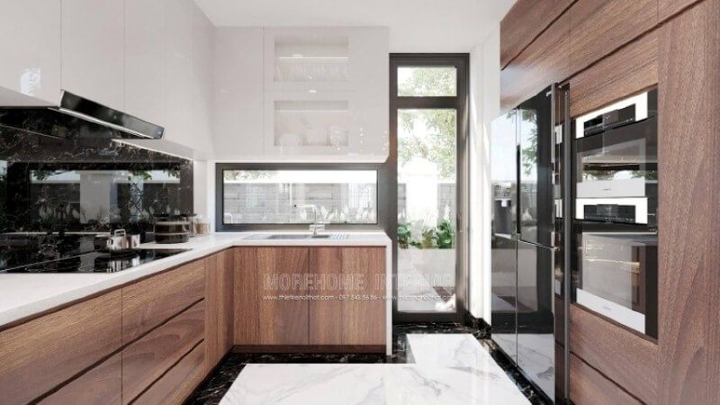 Là một trong những xu hướng thiết kế nội thất nổi bật trong những năm tới, bố trí phòng bếp hiện đại tôn lên vẻ đẹp mộc mạc nhưng không kém phần sang trọng của gỗ điển hình là gỗ óc chó tự nhiên. Loại gỗ rất được ưa chuộng trong các siêu xe bởi vẻ đẹp ấn tượng từ vân, màu gỗ. Như trong ý tưởng thiết kế phòng bếp tại biệt thự Vinhomes Imperia, sự hài hòa tôn lên nét đẹp giữa truyền thống và hiện đại, tủ bếp dưới gỗ óc chó veneer và tủ bếp trên gỗ công nghiệp trắng bóng.